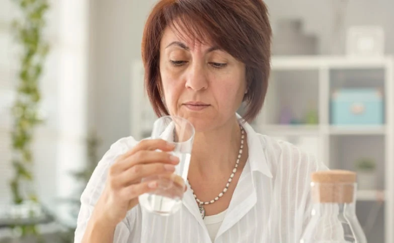 a woman looking at a cup of water suspiciously