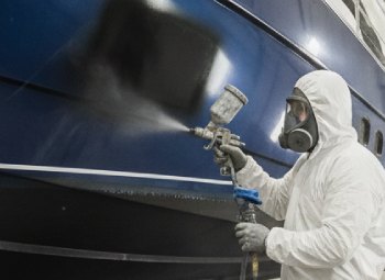 worker painting a boat with industrial paint